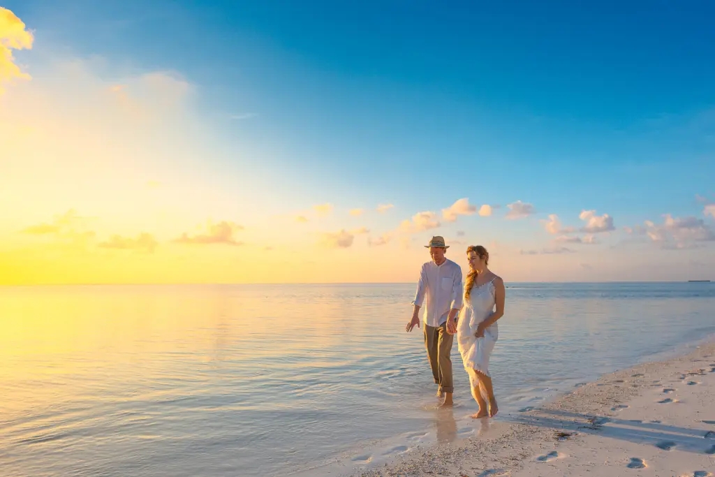 couple walking along the seashore at sunrise or sunset